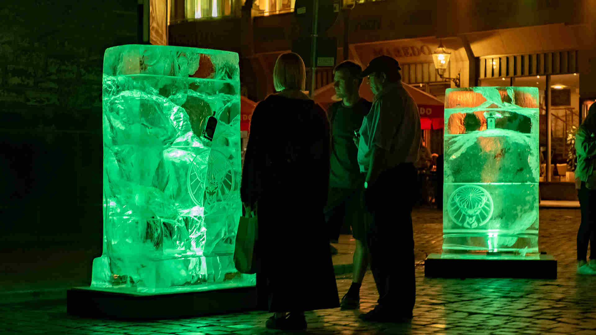 Zielgruppe schaut auf neongrün illuminierte Eisblock-Plakate von Jägermeister