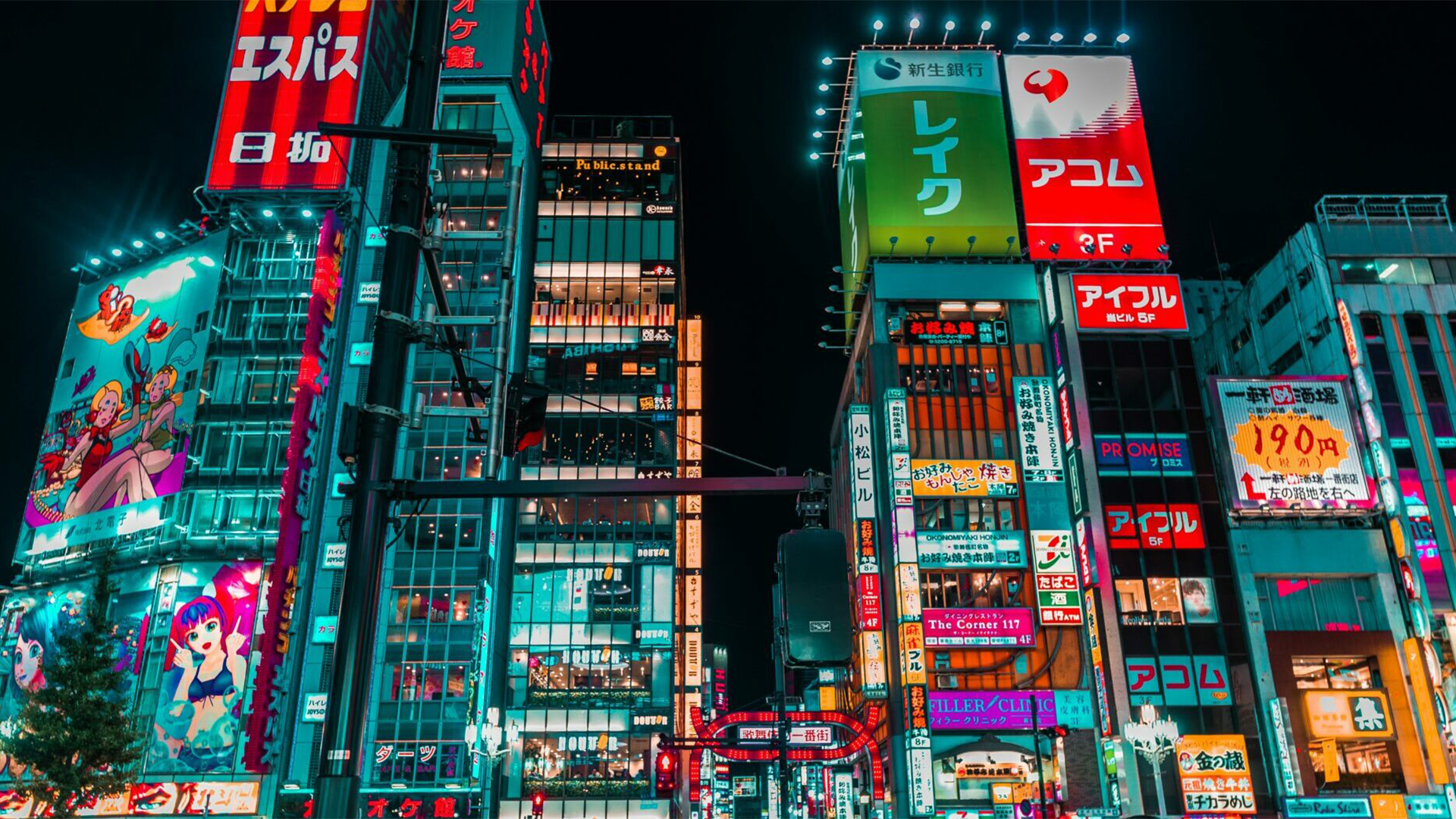Eine dicht bebaute Straßenkreuzung in der Nacht mit unzähligen leuchtenden Reklametafeln. Bunte Schriftzeichen, Logos und großflächige Illustrationen erhellen die Fassaden der Hochhäuser. Die Szene wirkt lebendig und farbenfroh wie ein urbanes Lichtermeer.