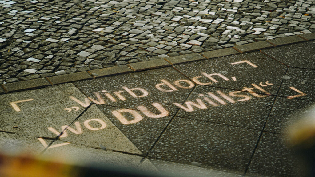 Auf dem Gehweg erscheint ein KreideStencil von INOVISCO mit dem Slogan „Wirb doch, wo DU willst!“. Die Botschaft hebt sich klar vom Pflaster ab und zieht die Blicke der Passanten an.