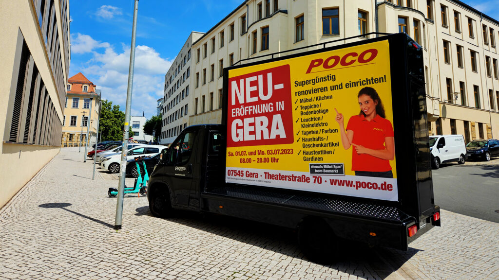 Innenstadt mit einem CoolLiteTruck 18/1. Auf dem CoolLiteTruck 18/1 wird ein Werbemotiv von POCO angezeigt zur Filialeröffnung.