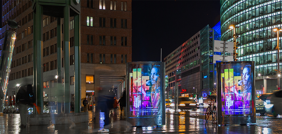 In der Berliner Innenstadt stehen bei Dunkelheit zwei INOVISCO CoolLiteMover und zeigen eine besonders gut sichtbare Werbung, weil sie hinterleuchtete sind.