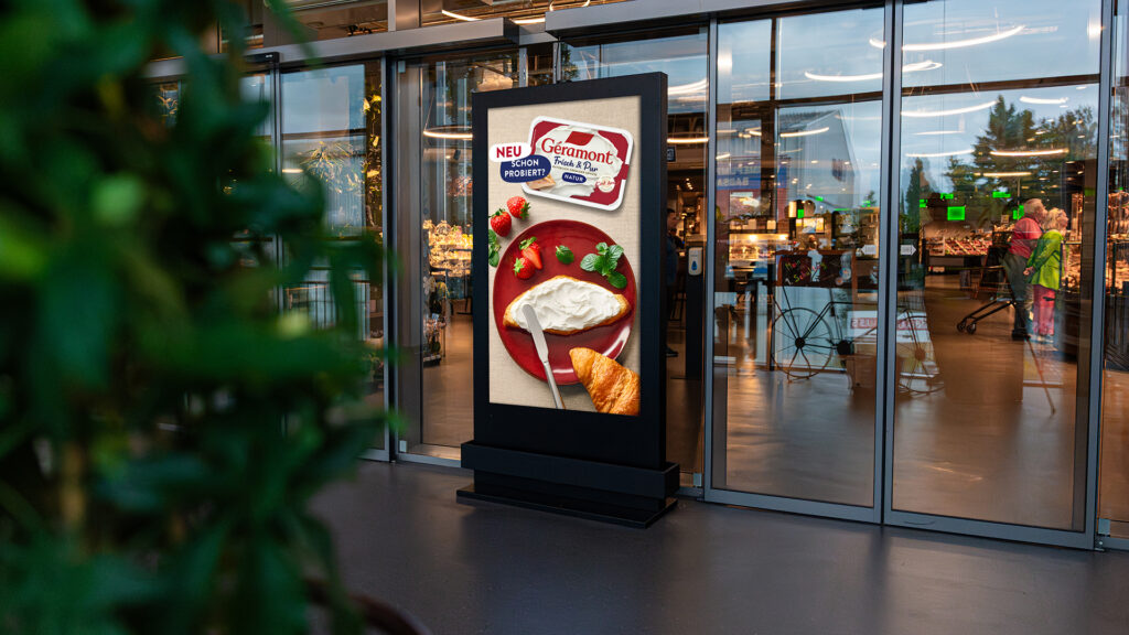 Zwischen zwei Eingängen eines EDEKA Marktes ist ein DCLP von INOVISCO, Dieser zeigt eine ANzeige von Géramont.