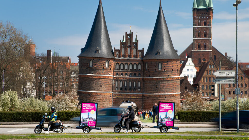 Zwei INOVISCO-CoolLiteScooter stehen vor dem Holstentor in Lübeck und zeigen eine Werbekampagne von Telekom.