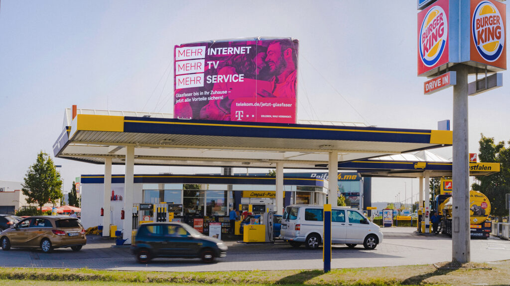 Von der Straße aus fotografiert, ist eine Tankstelle zu sehen, die auf Ihrem Dach ein INOVISCO StationLight trägt.